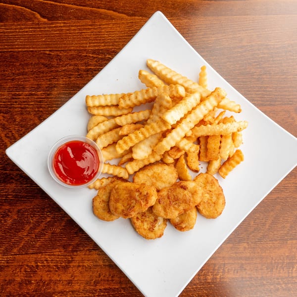A white plate with crispy crinkle-cut fries, golden chicken nuggets, and a side of ketchup.