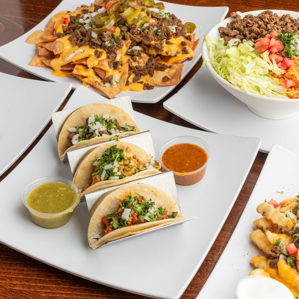 A variety of Mexican dishes, including tacos, nachos, a burrito bowl, and loaded fries.